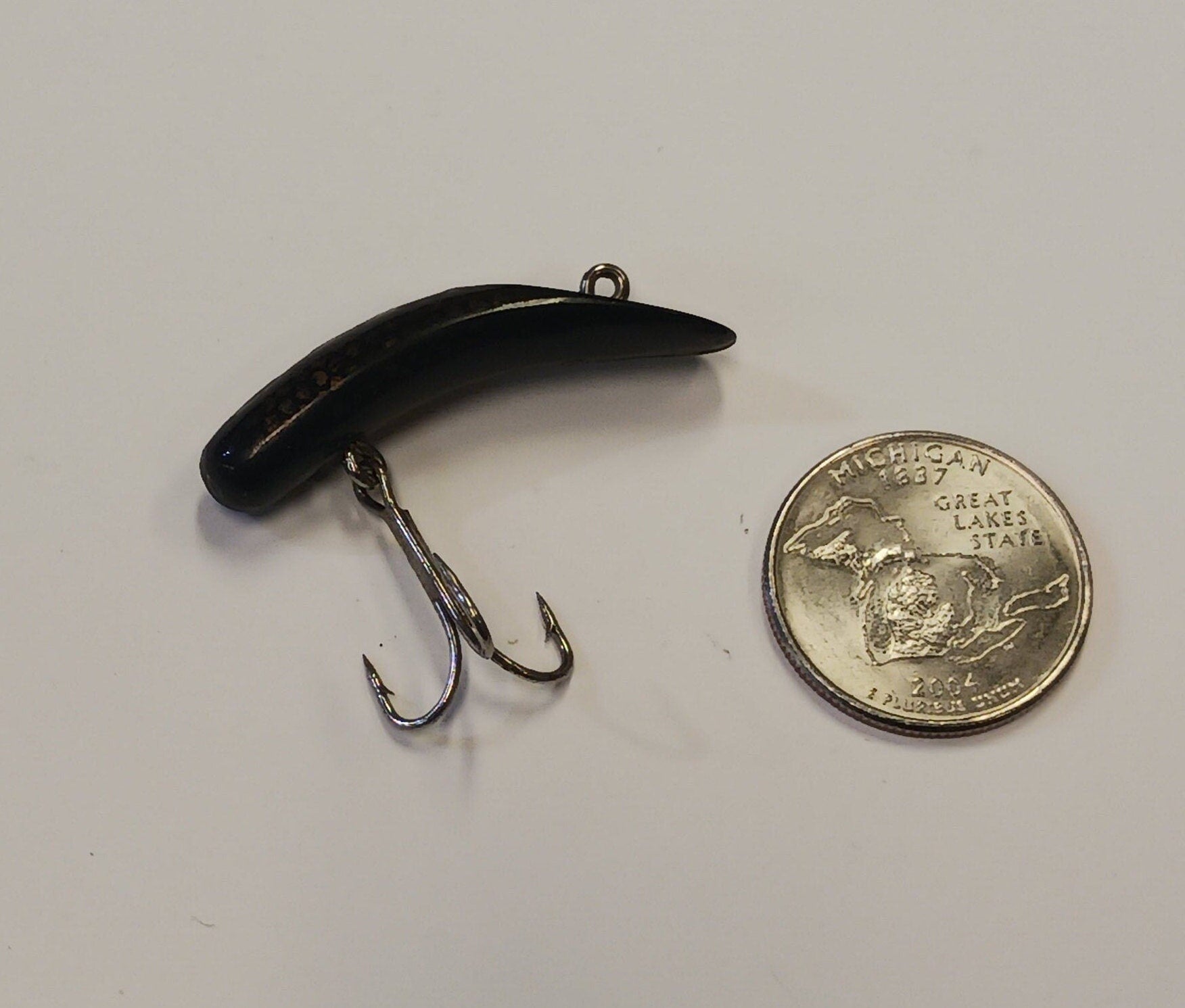 Fishing lure next to a quarter on a white background